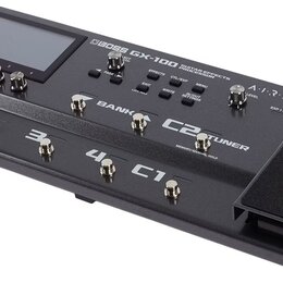 Černý kytarový efektový procesor s displejem a ovládacími prvky. Na horní části je nápis BOSS GX-100 GUITAR EFFECTS PROCESSOR a logo AIRD. Přístroj o…