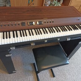 Digitální piano v dřevěném korpusu s hnědým povrchem, vybavené klávesnicí a černou stoličkou. Na horním panelu je nápis YAMAHA a řada ovládacích prvk…