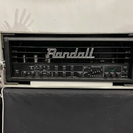 Černý kytarový zesilovač značky Randall umístěný v transportním kufru. Na předním panelu jsou ovládací knofíky a přepínače s nápisy GAIN, LEVEL, BASS…