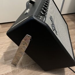 Černý kytarový kombo zesilovač s bílou textilní maskou a kovovými prvky. Na horním ovládacím panelu je nápis STRATOCASTER a logo Fender. Zesilovač má…