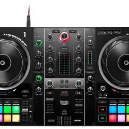 Černý DJ kontrolér s dvěma velkými jog-koly, centrálním mixážním sekcí a podsvícenými pady v spodní části. Na horní hraně jsou nápisy 1 a 2 u jednotl…