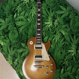 Elektrická kytara typu Les Paul v žlutohnědé barvě s hnědým přechodem. Na hlavě je nápis "Epiphone" a logo. Kytara má dva humbuckery, čtyři ovládací…