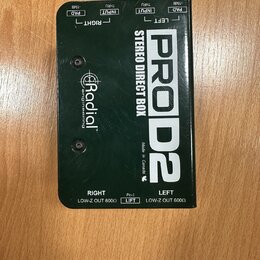 Černá stereo DI box s kovovým povrchem a bílými nápisy. Na horní straně jsou popisky PAD -15dB, INPUT a THRU pro kanály RIGHT a LEFT. Uprostřed je uv…