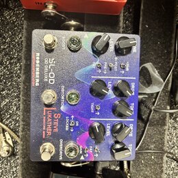 Kytarový efekt pedál s kovovým šasi a fialovo-modrým gradientním povrchem. Na pedálu jsou nápisy RODENBERG, SL-OD DELUXE, CUSTOM AMPLIFICATION a STEV…