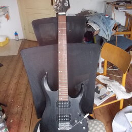 Černá elektrická kytara s dvojcutem a černým hardwarem. Na hlavě hmatníku je bílý nápis Cort. Kytara má dva humbuckery, jeden potenciometr a jeden př…