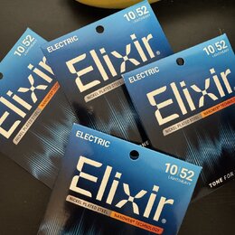 Čtyři balení strun pro elektrickou kytaru značky Elixir. Na každém obalu je uveden nápis ELECTRIC, NICKEL PLATED STEEL a NANOWEB® TECHNOLOGY s označe…