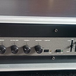 Černý basový zesilovač Ampeg B2R umístěný v hliníkovém transportním kufru. Na předním panelu jsou ovládací prvky s nápisy INPUT, PAD, GAIN, BASS, ULT…