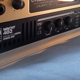 Detailní pohled na přední panel černého zesilovače s nápisy „MACHT 402“ a „SPECIALIZED GUITAR POWER AMP“. Vedle textu je umístěno logo s nápisem „Pal…