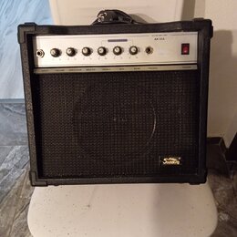 Černý kytarový kombo zesilovač s bílým ovládacím panelem a černou textilní maskou reproduktoru. Na panelu je nápis GUITAR AMPLIFIER, model AK30A a na…