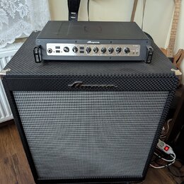 Černý basový kombozesilovač tvořený samostatnou hlavou a reproduktorovou skříní. Na předním panelu hlavy je nápis Ampeg a model PF-800, na přední str…