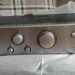 Stříbrný integrovaný stereo zesilovač s černým horním krytem a ventilační mřížkou. Na předním panelu jsou nápisy ONKYO, INTEGRATED STEREO AMPLIFIER a…