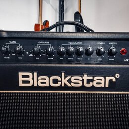 Detailní pohled na ovládací panel kytarového komba černé barvy. Na panelu jsou nápisy CLEAN, OVERDRIVE, EQUALISATION, REVERB a MASTER s řadou ovládac…