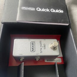 Stříbrný efekt pedál značky MXR v černé krabici, vedle kterého leží černý manuál s nápisem Dunlop Quick Guide. Na pedálu jsou nápisy MXR, trs split +…