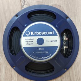 Modrý kruhový reproduktor s černou membránou. Uprostřed je bílá nálepka s modrým logem a nápisy Turbosound, Designed and Engineered in England, TS-8G…
