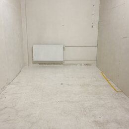 Fotografie znázorňuje prázdnou místnost s bílými stěnami a světlou betonovou podlahou. Na zadní stěně je umístěn bílý panelový radiátor. V pravém dol…