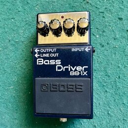 Modrý efekt pedál s nápisy Bass Driver a BB-1X. Horní část je z anodizovaného kovu se čtyřmi ovládacími knoflíky, červenou kontrolkou a nápisem CHECK…