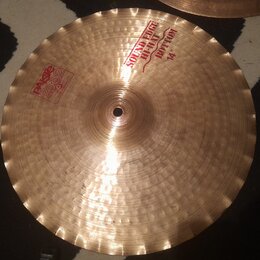 Kovový činel v zlatavé barvě s viditelným klepaným povrchem a vlnitým okrajem. Na povrchu je červený nápis SOUND EDGE HI-HAT BOTTOM 14" a logo Paiste…