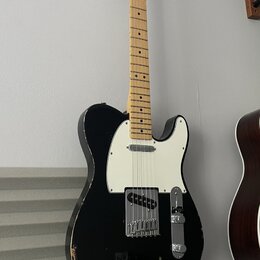 Černá elektrická kytara typu Telecaster s bílým pickguardem a světlou hmatníkovou deskou. Nástroj vykazuje známky opotřebení v podobě odlakování na s…