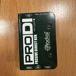 Černá pasivní DI box s nápisy PRODI a PASSIVE DIRECT BOX. Na povrchu je logo Radial engineering a text Made in Canada. Jsou zde viditelné popisky vst…