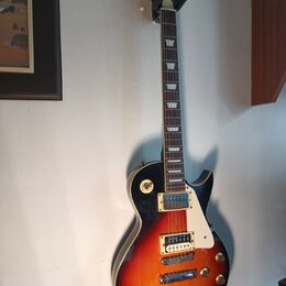 Elektrická kytara s tvarem singlecut a barevným přechodem od černé k oranžové. Na hlavě hmatníku je nápis "Gibson" a pod ním text "LES PAUL MODEL". N…