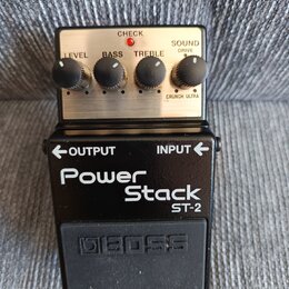 Černý efekt pedál s kovovým horním panelem. Na panelu jsou čtyři ovládací knoflíky s popisky LEVEL, BASS, TREBLE a SOUND DRIVE (s volbou CRUNCH ULTRA…