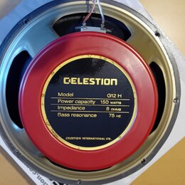 Fotografie zachycuje zadní stranu reproduktoru s červeným magnetem. Na magnetu je černý štítek se zlatým nápisem CELESTION a specifikacemi: Model G12…