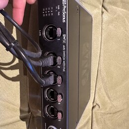 Černý síťový switch s bílými detaily a nápisy. Na zařízení je vidět logo Presonus a text SW5E AVB SWITCH WITH POE. Přístroj obsahuje pět RJ45 portů,…