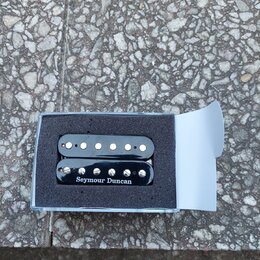 Dvě černé elektrické snímače typu humbucker v originální modré krabičce s pěnovou výplní. Na spodním snímači je bílý nápis Seymour Duncan. Snímače ma…