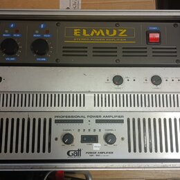 Fotografie zachycuje dva rackové výkonové zesilovače umístěné v transportním kufru. Horní zařízení je černé s nápisem ELMUZ STEREO POWER AMPLIFIER, m…