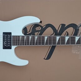 Bílá elektrická kytara s černým hardwarem a hmatníkem. Na hlavě je bílý nápis Jackson. Kytara má dva humbuckery, jeden tónový a jeden hlasitostní pot…