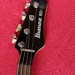 Detail hlavy černé basové kytary s nápisem Ibanez RDGR ROADSTAR. Na hlavě jsou čtyři chromované ladičky a viditelný nápis Ibanez RDGR ROADSTAR v bílé…