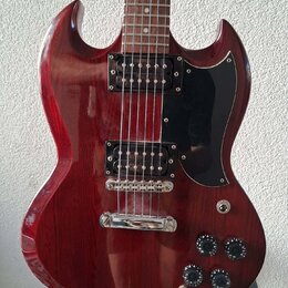 Tmavě červená elektrická kytara s hnědým hmatníkem a černým pickguardem. Nástroj je vybaven dvěma humbuckery, stříbrným mostem a čtyřmi černými ováln…