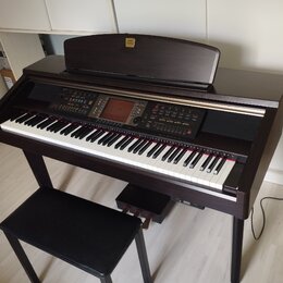 Tmavně hnědý digitální piano s klaviaturou, ovládacím panelem a přívodním kabelem. Na horní části je nápis "KORG Clavinet". Součástí je černá polstro…