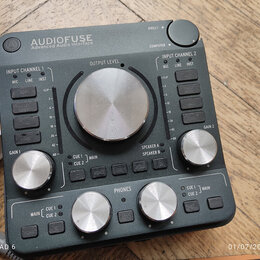 Tmavě šedý audio rozhraní s nápisem AUDIOFUSE Advanced Audio Interface. Zařízení obsahuje několik stříbrných otočných ovladačů s popisky GAIN 1, OUTP…