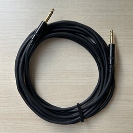 Černý audio kabel s pozlacenými 6,3mm jack konektory na obou koncích. Kabel je svinutý do kruhu a upevněný černým suchým zipem. Povrch kabelu i konek…