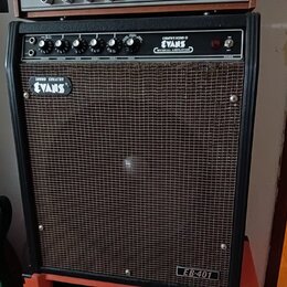 Černý kytarový kombo zesilovač s hnědou textilní maskou. Na ovládacím panelu jsou nápisy CREATIVE SOUND ® EVANS MUSICAL AMPLIFIER a popisky ovladačů…