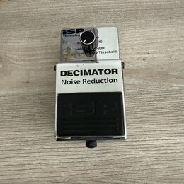 Kovový efekt pedál stříbrné barvy s černým nápisem DECIMATOR Noise Reduction. V horní části je ovládací knoflík s nápisy isp Technology, -50, -60, -1…
