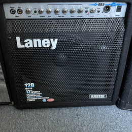 Černý basový kombozesilovač značky Laney, model RB5. Přední mřížka je z černého kovu s velkým bílým nápisem Laney a v dolní části štítkem s textem 12…