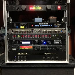 Stříbrný rackový kufřík s několika zařízeními. Obsahuje jednotky s nápisy KORG, The Rocket VM-100, ROCKTRON TriAxis, ROCKTRON HUSH a Mesa/Boogie Fift…