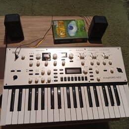 Bílý syntetizátor s klaviaturou, na kterém je vlevo nápis KORG a vpravo KingKORG NEO. Přístroj obsahuje řadu bílých otočných ovladačů, tlačítek a dva…
