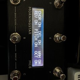 Černý MIDI kontrolér s nápisem MORNINGSTAR a označením MC6. Zařízení má šest kovových spínačů označených písmeny A, B, C, D, E a F, a nápisy BANK DOW…