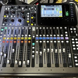 Digitální mixážní pult v černé barvě s řadou posuvníků, tlačítek a ovládacích knoflíků. V horní části je umístěn barevný displej a nápis X32 Compact.…