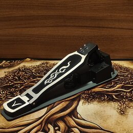 Černý bubenový pedál s hliníkovými stříbrnými prvky. Na horní části pedálu je vyrytý vlnitý ornament a v přední části symbol připomínající stylizovan…