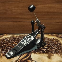 Šedý basový pedál s černými a stříbrnými prvky. Na stupni je bílý nápis TAMA a stylizované logo Iron Cobra, dále text The Legend in Innovation. Povrc…