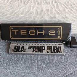 Na fotografii je kytarový pedál v hliníkovém šasi s nápisy TECH 21, SANSAMP PLEX! a DLA. Zařízení má tři stoupací spínače s popisy TAP, ON, ON a ON.…