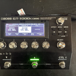 Černý kytarový procesor s nápisem BOSS GT-1000CORE GUITAR EFFECTS PROCESSOR. Zařízení má digitální displej, pět stříbrných otočných ovladačů v řadě,…