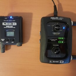 Na fotografii jsou dva černé přístroje značky LINE 6. Vlevo je vysílač s nápisy RELAY G50 TRANSMITTER a 2.4GHz DIGITAL WIRELESS SYSTEM, vybavený malý…