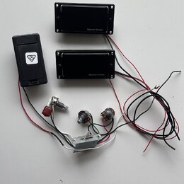 Dva černé humbuckery s nápisem Seymour Duncan, jeden černý plastový box s bílým logem v trojúhelníku a sada elektroniky. Soubor obsahuje dva potencio…