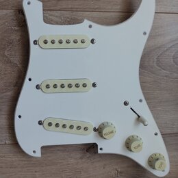 Bílá plastová pickguard pro elektrickou kytaru s třemi krky pro snímače typu single-coil. Na plastu jsou tři kroužky s nápisy VOLUME, TONE a TONE v b…