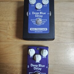 Dvě efektové pedály Deep Blue Delay značky MAD PROFESSOR, BJF DESIGN. Horní pedál je v černém kovovém boxu s modrým ovládacím panelem, spodní pedál m…